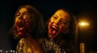 Two women with bloody faces screaming while on a motorcycle