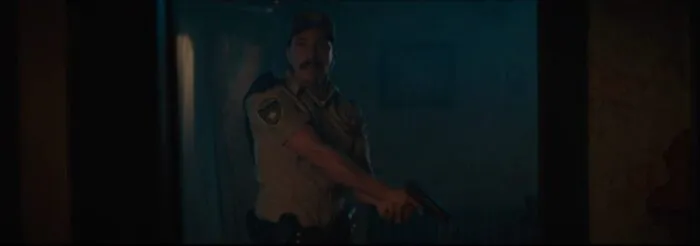 A policeman holding a gun in a dark house.