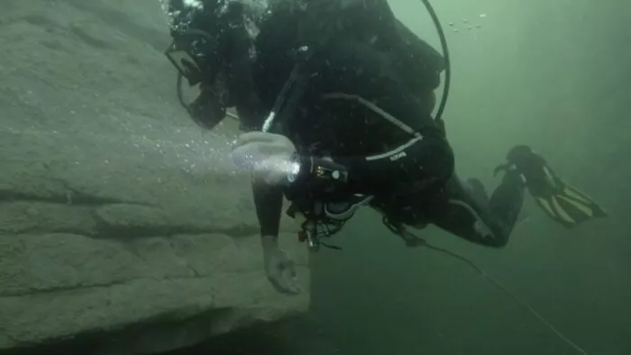 Chad swims through the cave, getting ready to take rock samples