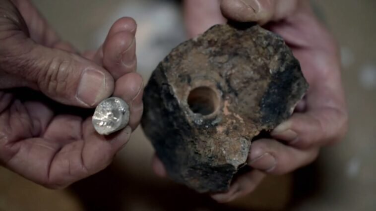 A close-up of a piece of rock with a hole in it, and a corresponding cylinder of mystery metal.