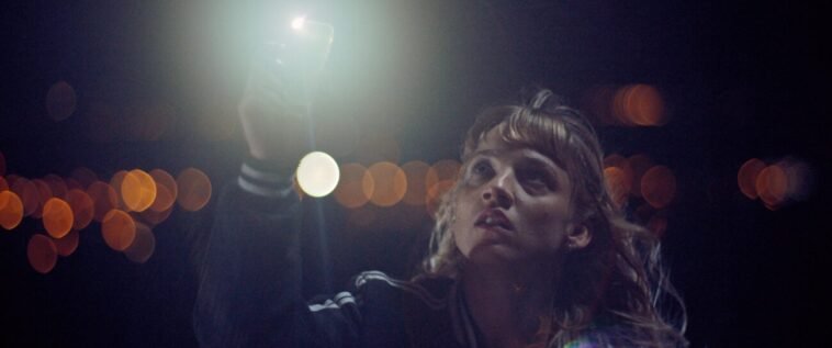 A woman holding up a cell phone at night