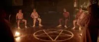 Two men tied to chairs in circles outside of a pentagram contained in a circle.