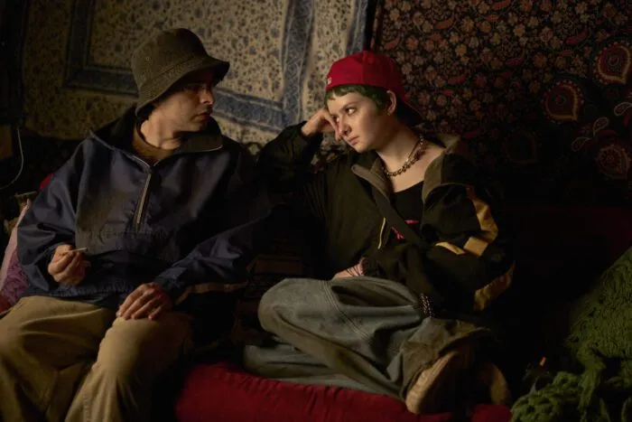 Two '90s dressed people having a conversation on a couch in Y2K.
