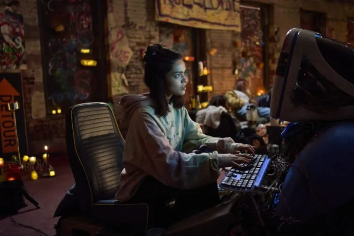 A young woman sits at a computer desk.