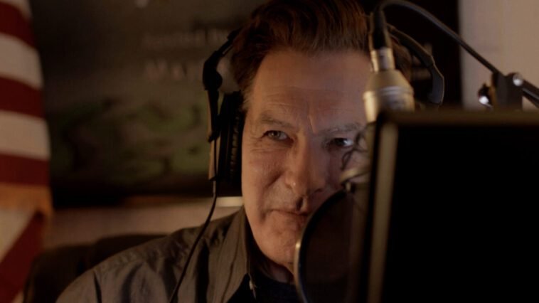 A man with headphones on sitting at a microphone