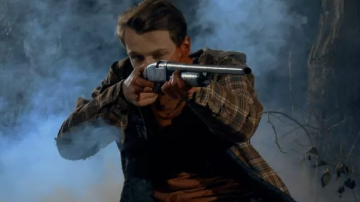 A man shrouded in fog holds up a rifle.