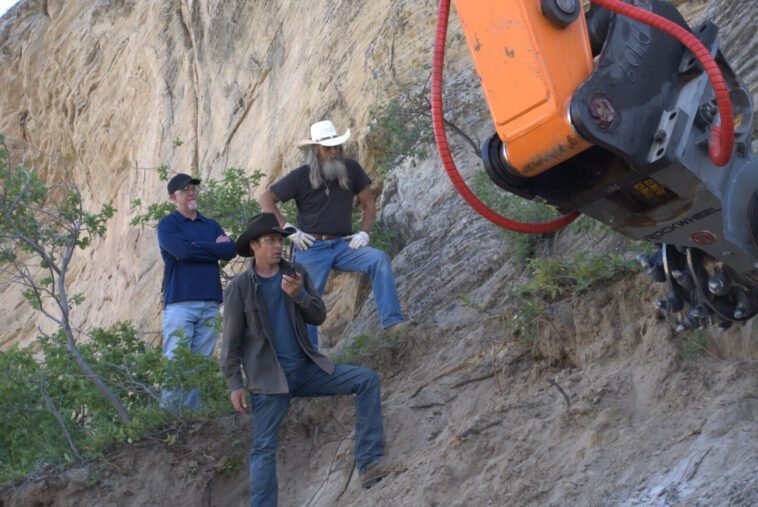 Josh Feldman, James Keenan, and Charlie Snider look on as the excavator cuts into the rock.