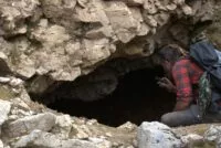 Chad Ollinger shines his flashlight into a cavern.