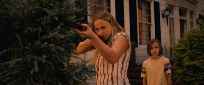 A young woman looks down the sights of a rifle she's aiming.