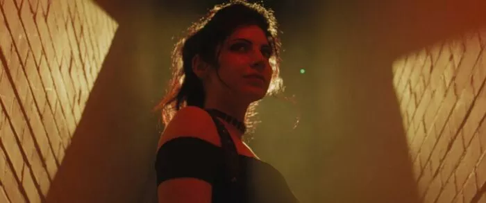 A confident looking woman stands in a spotlight