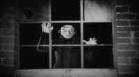 A pale vampire seen through the cage of a window pane missing its glass. The image is analyzed in NOSFERATU: THE REAL STORY