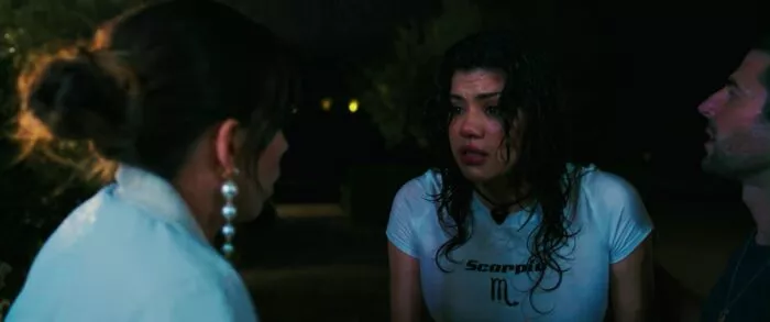 Two women are speaking in a garage while it rains in the backdrop of WHEN IT RAINS IN LA