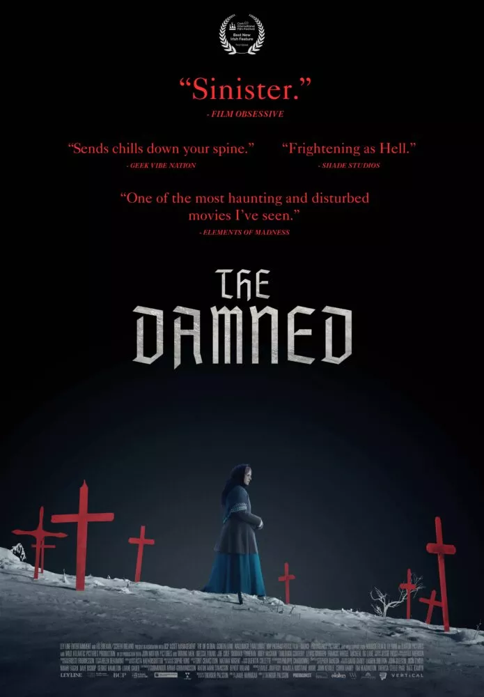 The poster for THE DAMNED shows a woman walking down a showy hillside surrounded by red crosses
