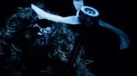 A masked man holds a weed whacker in THE WEEDHACKER MASSACRE