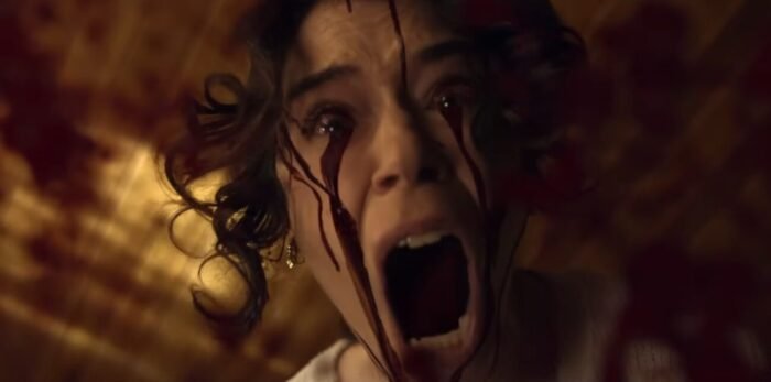 A woman screams while blood streams down her cheek from her eyes