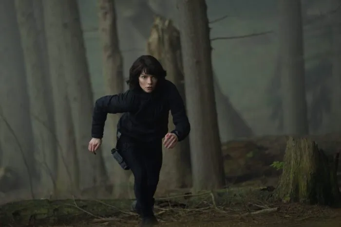 A woman running up a woody hillside