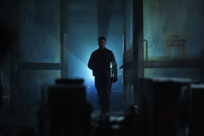 A man stands in a doorway, a light creating streaks behind him