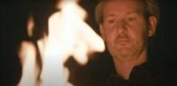 A CURSED MAN looks into the rising fire
