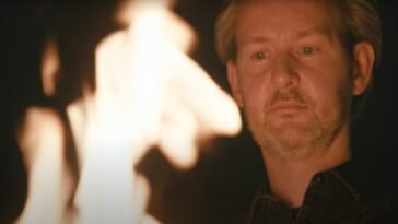 A CURSED MAN looks into the rising fire