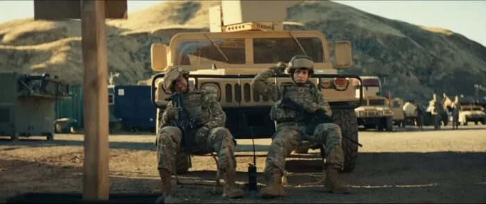 Two women soldiers sit in front of a Humvee