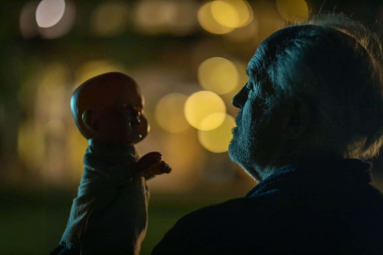 A man looks at a baby doll under the cover of darkness in THE RULE OF JENNY PEN