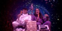 Two women enjoy ice cream in a colorful wormhole while eating ice cream in TIME TRAVEL IS DANGEROUS