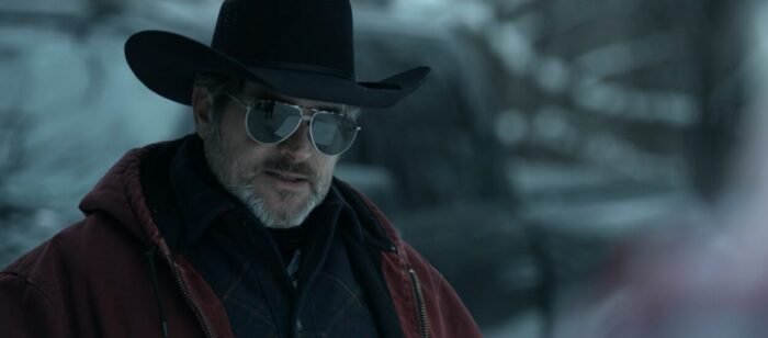 A man in a cowboy hat and aviator sunglasses