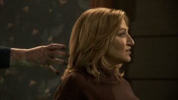 a hand reaches into the hair of a woman who is looking in the oppositte direction.