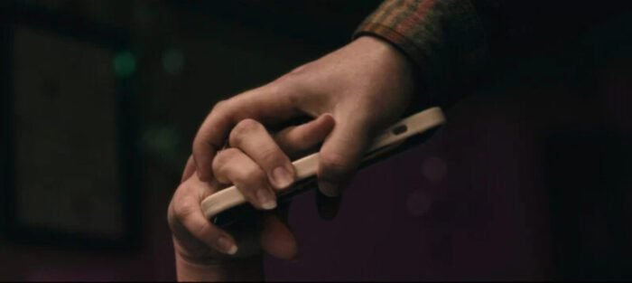 A hand grabbing another person's hand who is holding a phone.