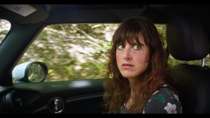 A woman looks worried while sitting in a car's passenger seat.