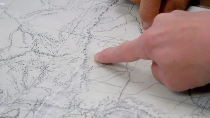 James points at a portion of the map that may have a new cave opening