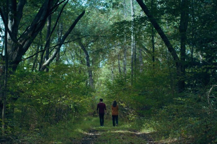 two people are seen working under a forest canopy in 825 FOREST ROAD