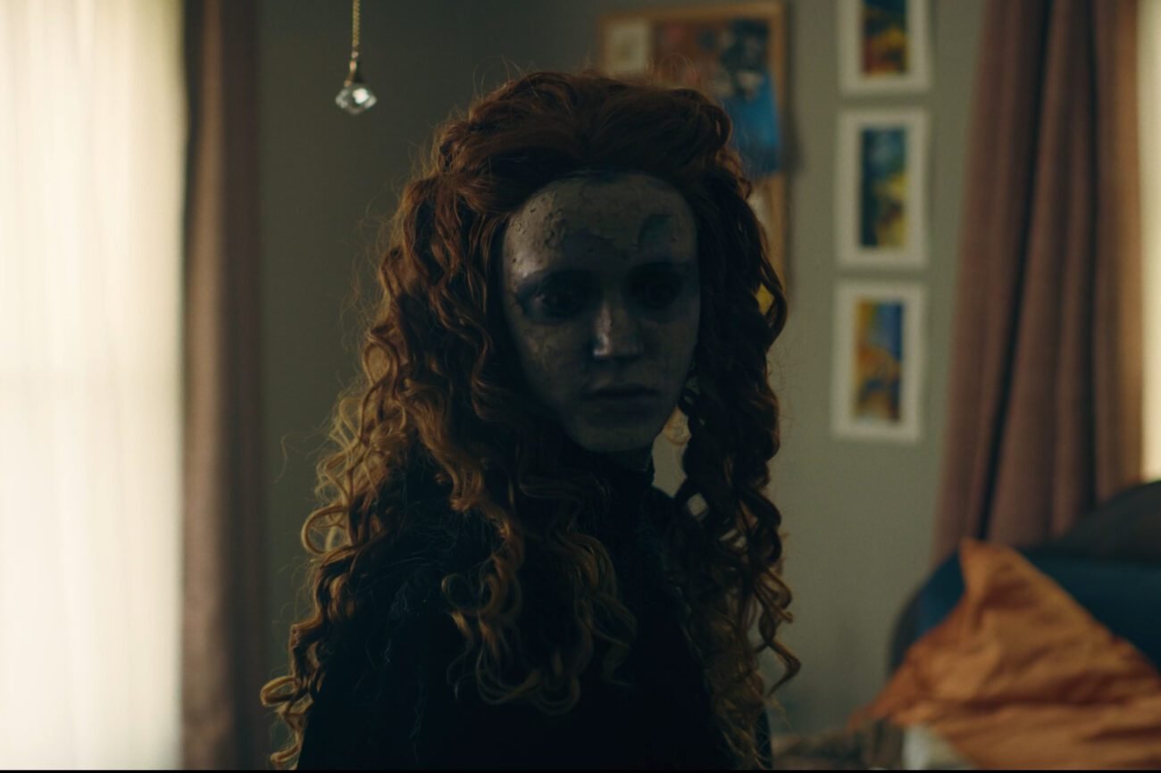 A woman with long hair wearing a porcelain mask