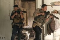two men holding powerful riffles and wearing body armor emerge from a doorway in THE ACCOUNTANT 2
