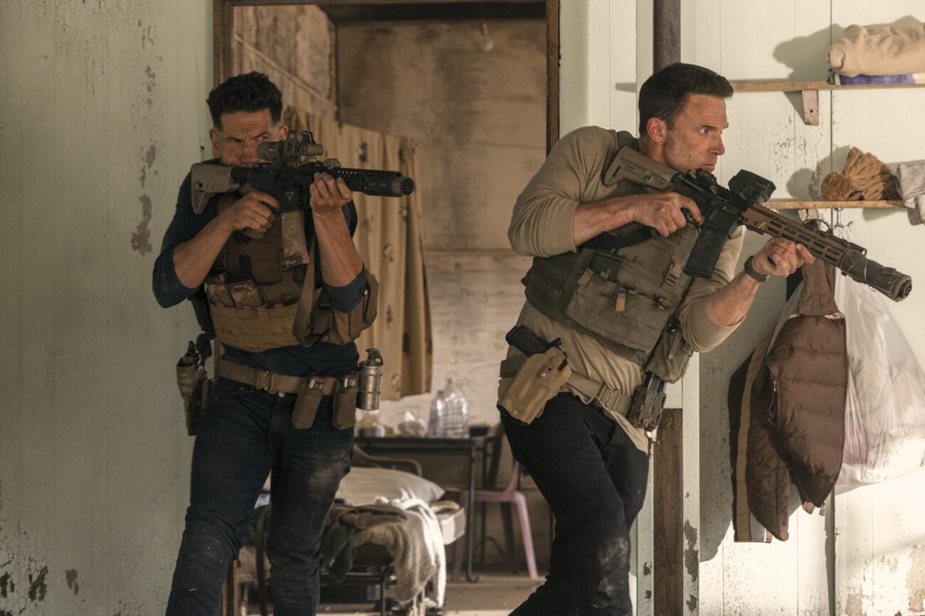 two men holding powerful riffles and wearing body armor emerge from a doorway in THE ACCOUNTANT 2