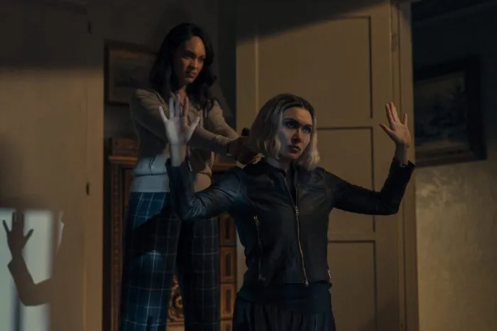 A woman holds a gun to the head of another woman dressed in leather on her knees in THE ACCOUNTANT 2