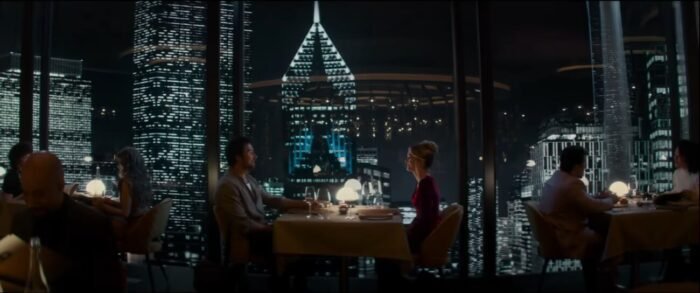Two people sitting at a restaurant table overlooking a city skyline