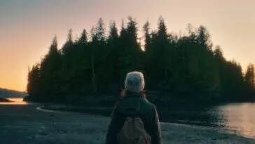 A woman looks toward an island at sunset in THE ISLAND BETWEEN TIDES