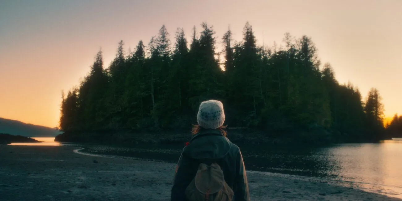 A woman looks toward an island at sunset in THE ISLAND BETWEEN TIDES
