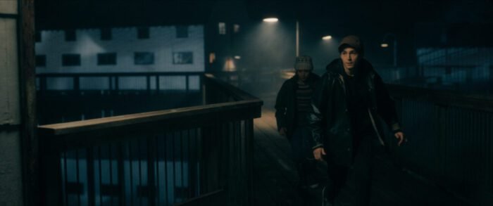 two figures walk under streetlamps along the pier.