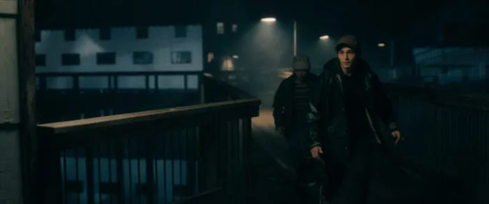 two figures walk under streetlamps along the pier.