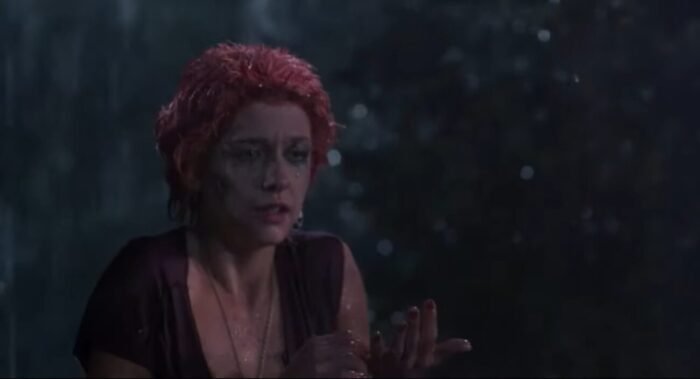 A woman looks on in terror while caught in the rain in a graveyard
