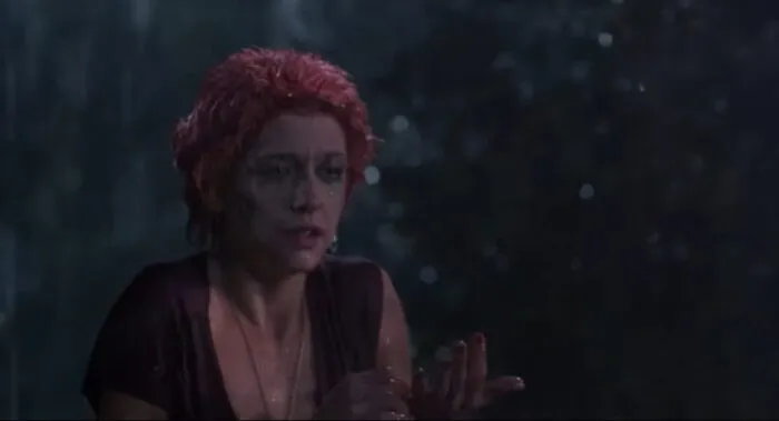 A woman looks on in terror while caught in the rain in a graveyard