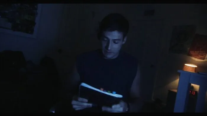 a man in a tank top holding a notebook.