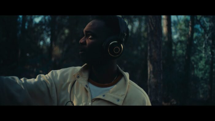 A man wearing headphones in the woods.