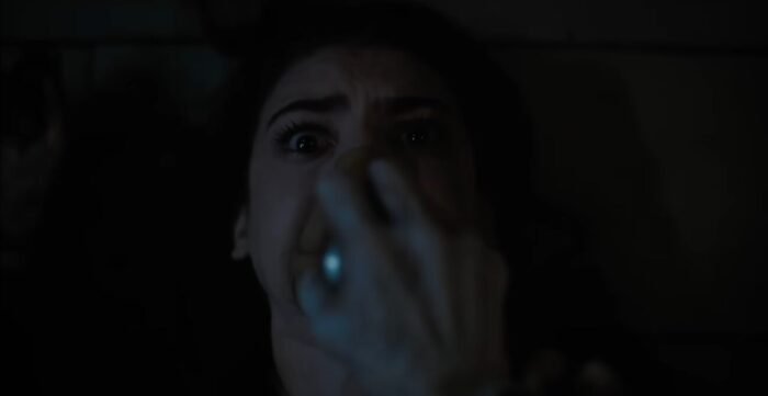 A woman with a breathing apparatus being held against her mouth
