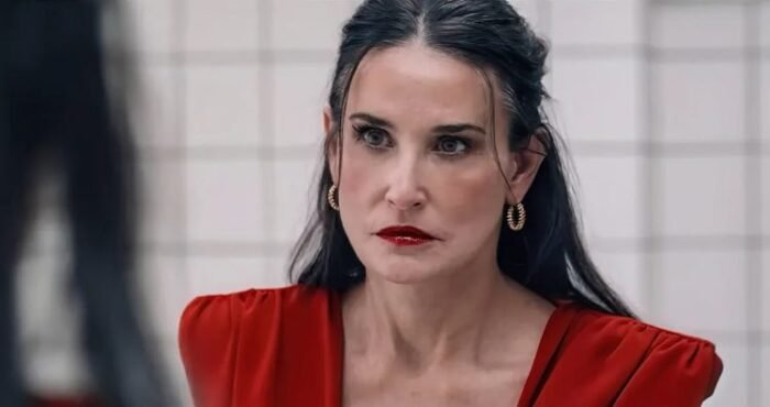 a woman in a red dress and red lipstick stares into a mirror