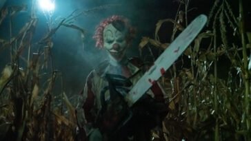A clown carries a large chainsaw through a cornfield in CLOWN IN A CORNFIELD