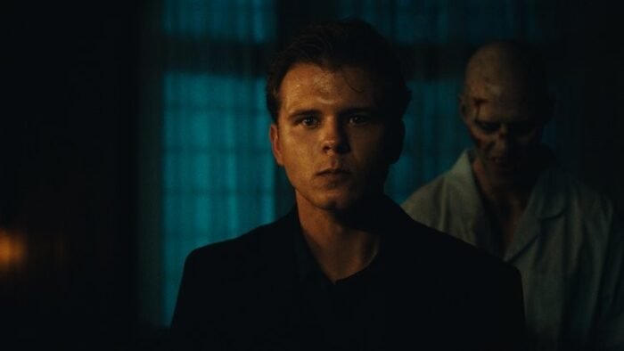A threatening figure stands behind a well-dressed man