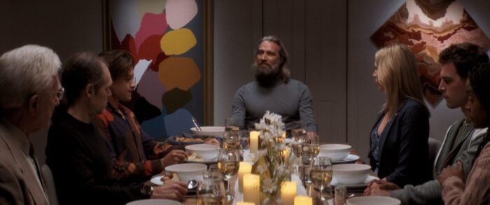 A dinner scene where guests are sat around a large dining room table.
